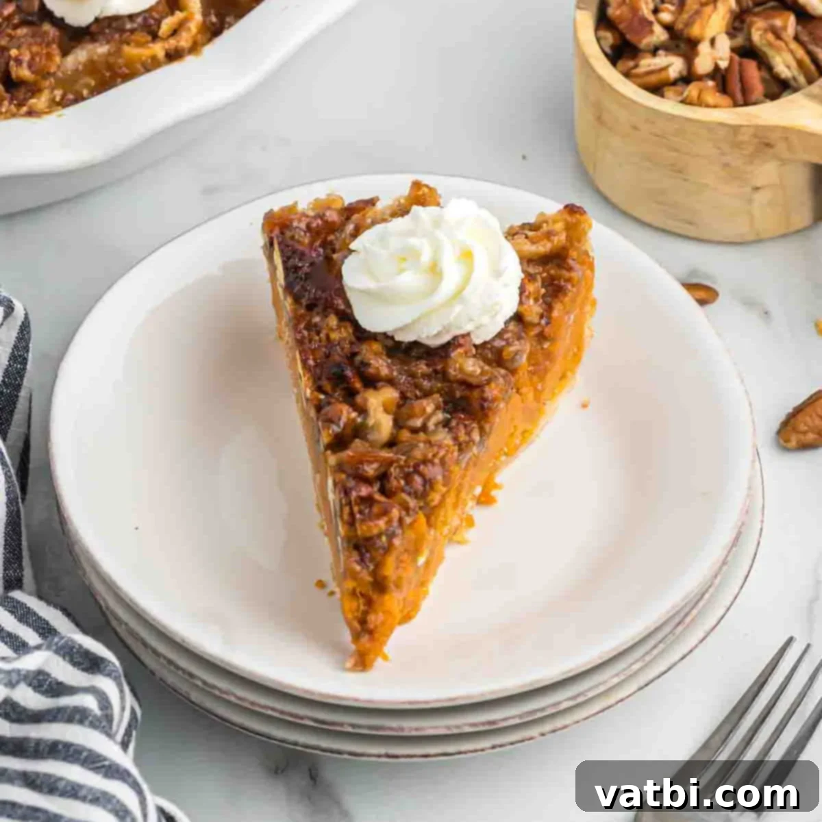 Southern Sweet Potato Pecan Pie 7 A slice of sweet potato pecan pie on a white plate, topped with a generous swirl of cool whip, ready to be enjoyed.