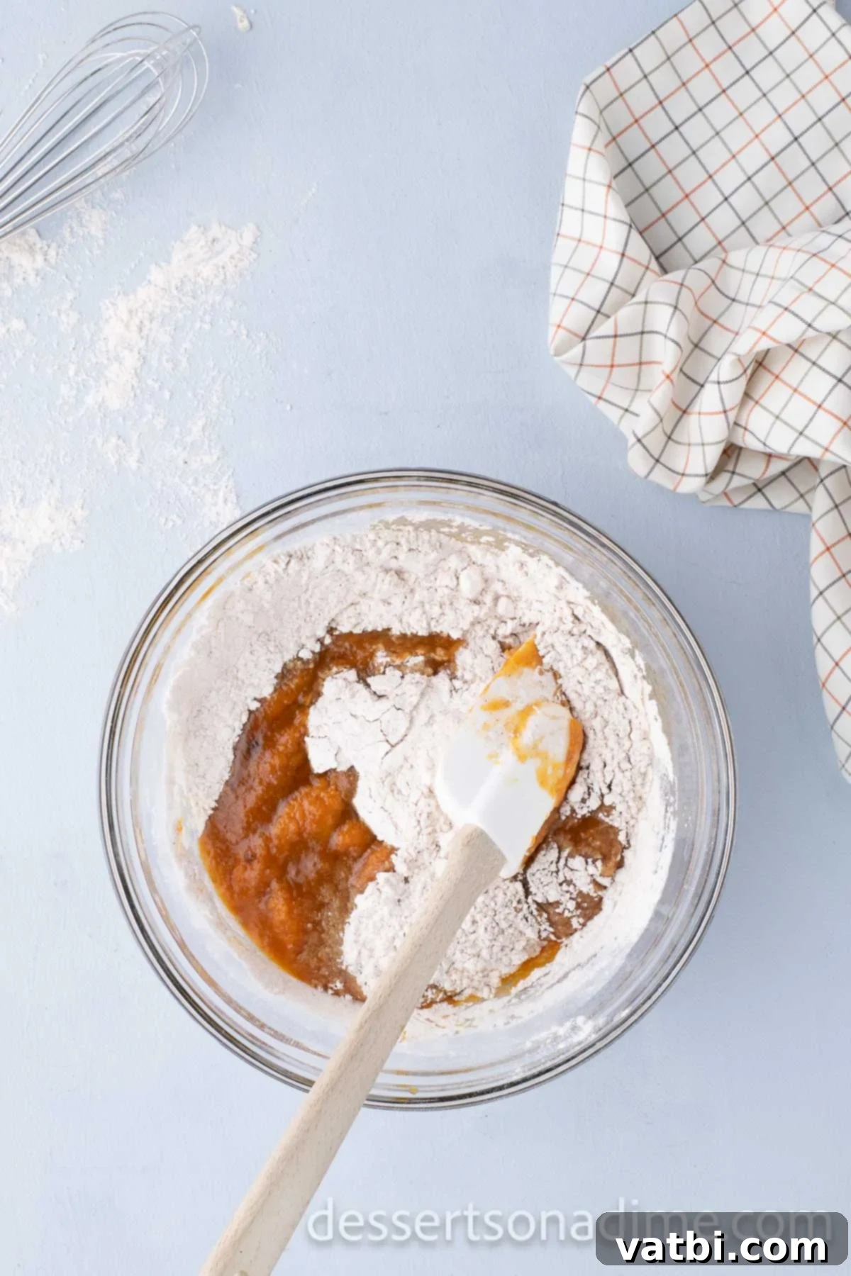 The wet and dry cupcake ingredients are gently folded together in a mixing bowl until just combined.