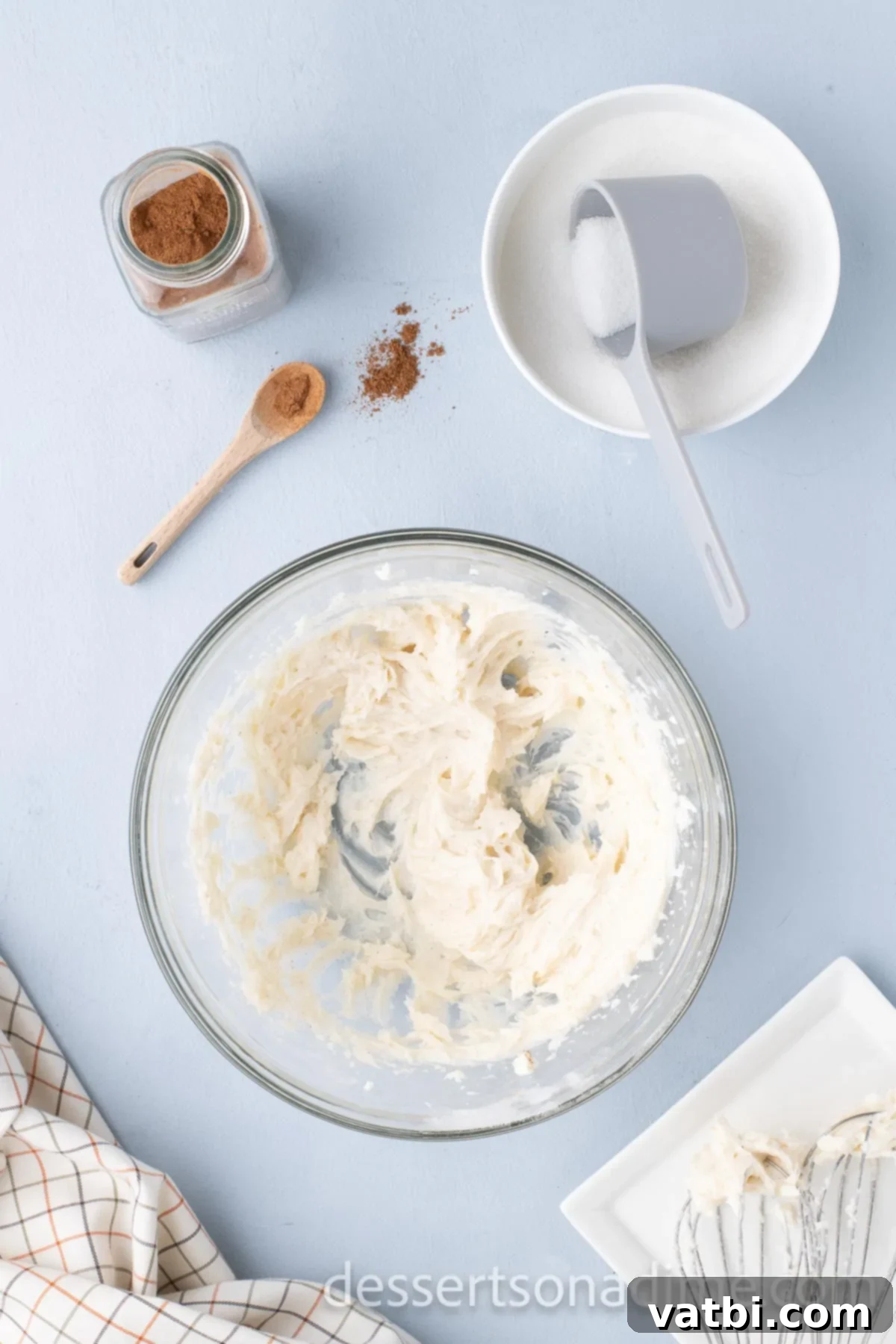 Cheesecake filling ingredients, including softened cream cheese, sugar, and pumpkin pie spice, beaten until smooth in a mixing bowl.
