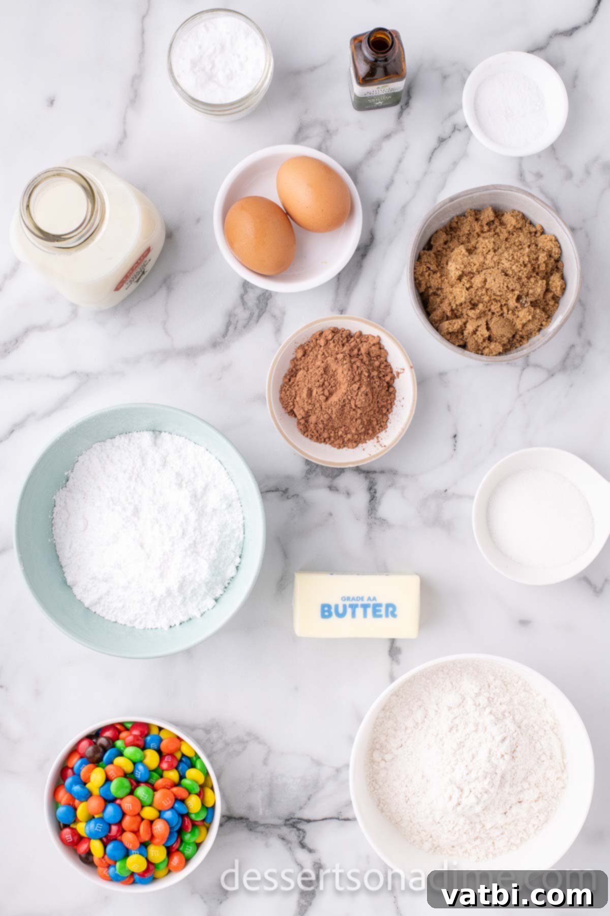 Ingredients for M&M cookie cake - butter, brown sugar, granulated sugar, eggs, vanilla, M&Ms, cocoa powder, butter. 