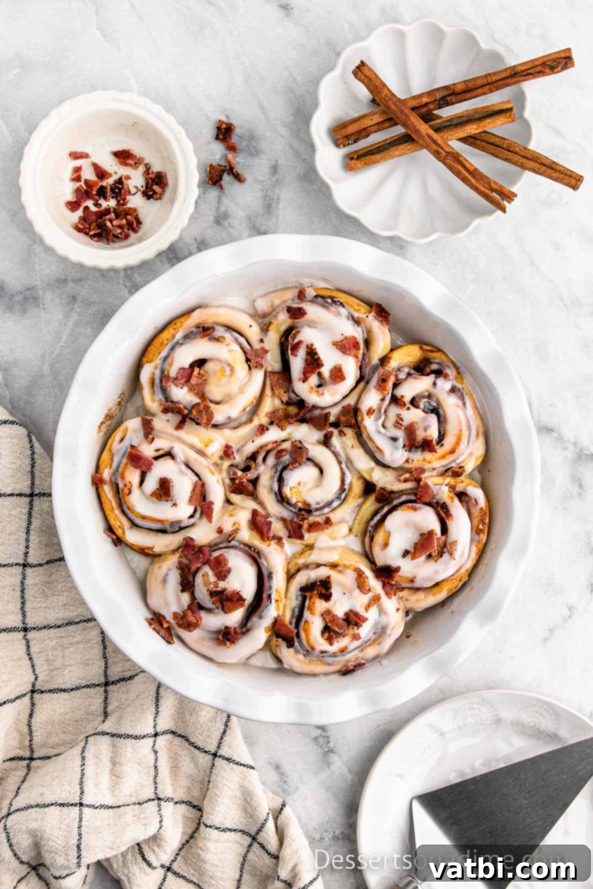 Decadent Bacon Cinnamon Buns 9 Freshly baked and iced bacon cinnamon rolls, garnished with additional chopped crispy bacon bits, ready to be served.