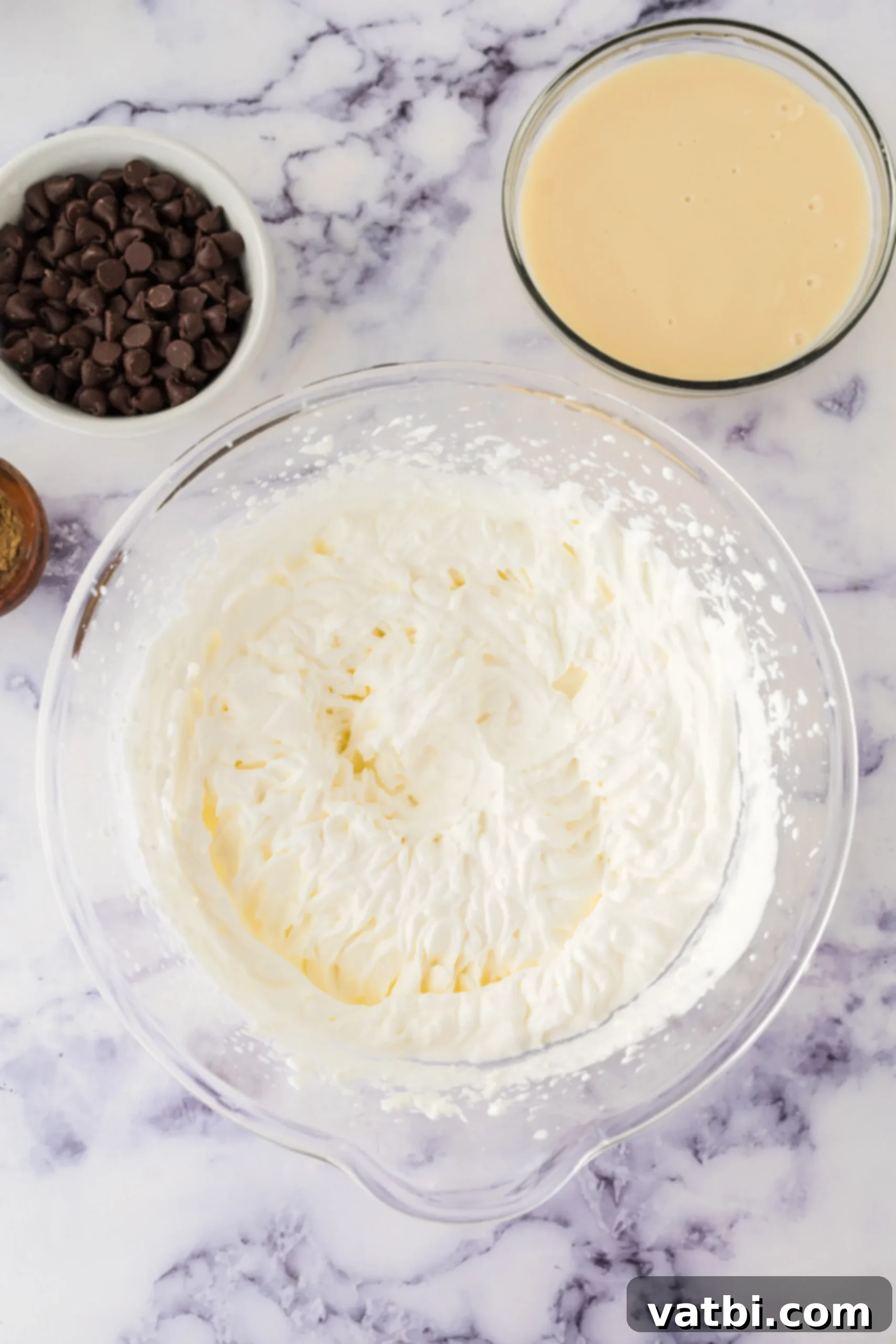 Spiced Pumpkin Chocolate Chunk Dream 4 A large mixing bowl with heavy cream being whipped by an electric hand mixer, showing the cream starting to thicken