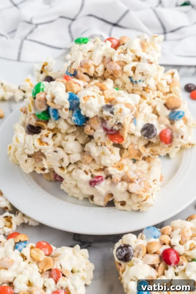 Homemade Popcorn Delight Bars 2 Delicious Popcorn Bars, cut into perfect squares and stacked on a white plate, ready to be enjoyed as a sweet and salty snack or dessert.