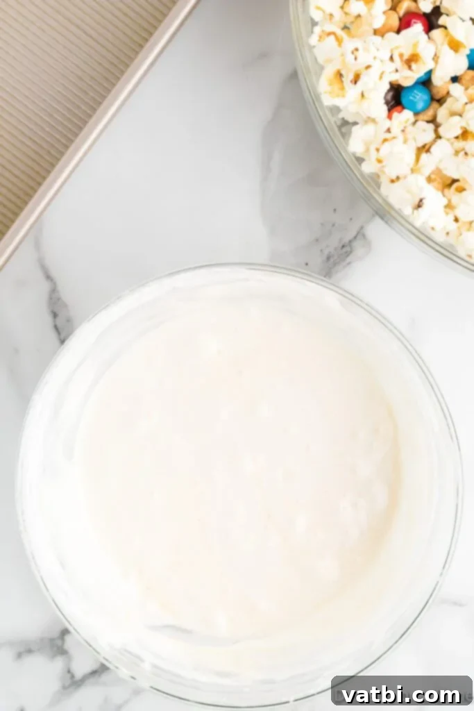Homemade Popcorn Delight Bars 6 The smoothly melted marshmallow mixture, perfectly gooey and ready to be poured over the popcorn and candy, in a glass bowl.