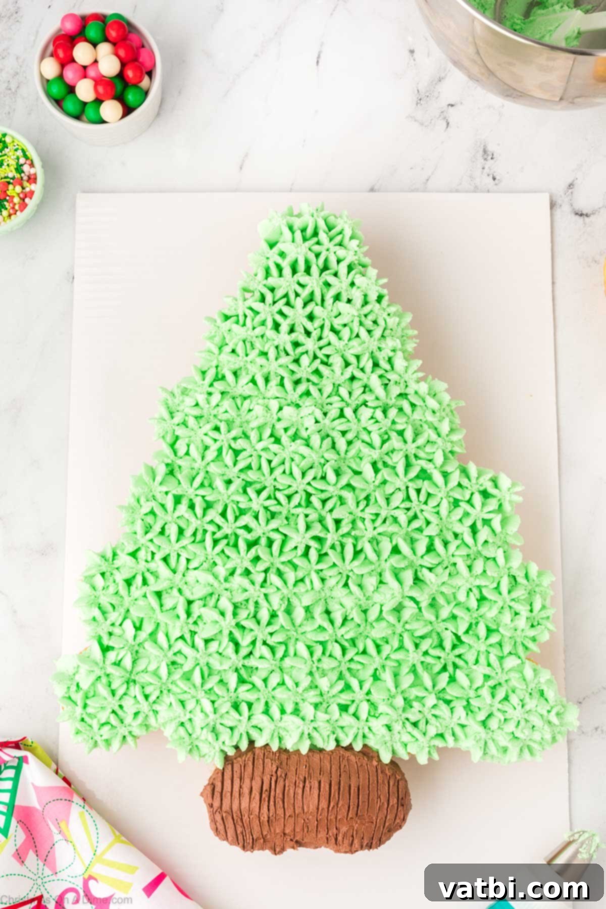 Green frosting piped with a large star tip over the entire Christmas tree cupcake cake, filling in gaps and creating a textured look.