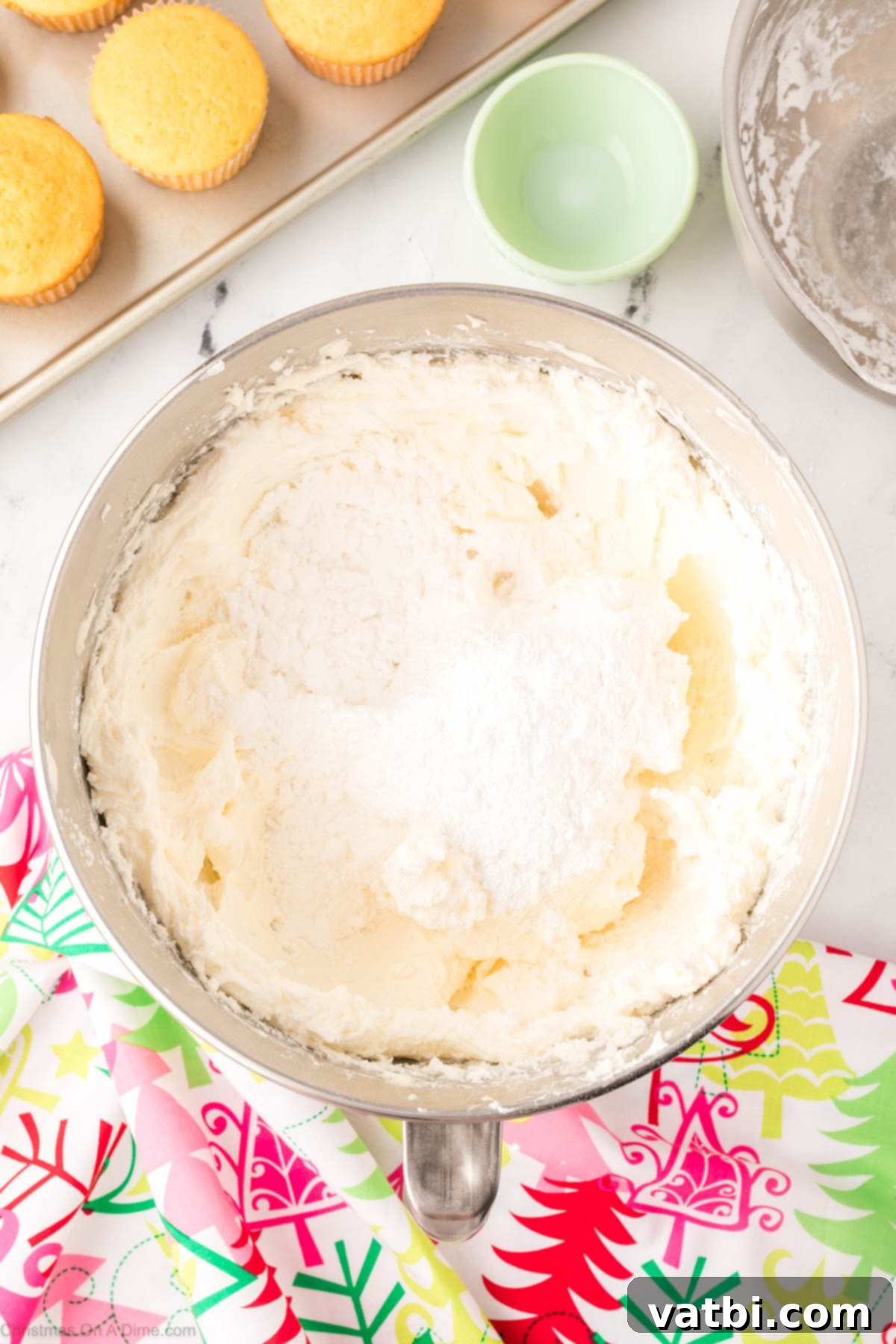 Sifted powdered sugar being added to the whipped butter and shortening mixture in a mixing bowl.
