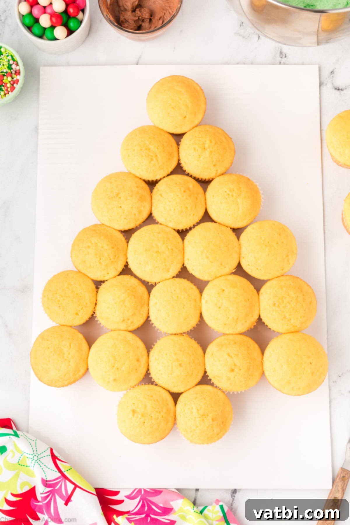 Vanilla cupcakes carefully arranged on a platter in the shape of a Christmas tree with two cupcakes at the base for the trunk.