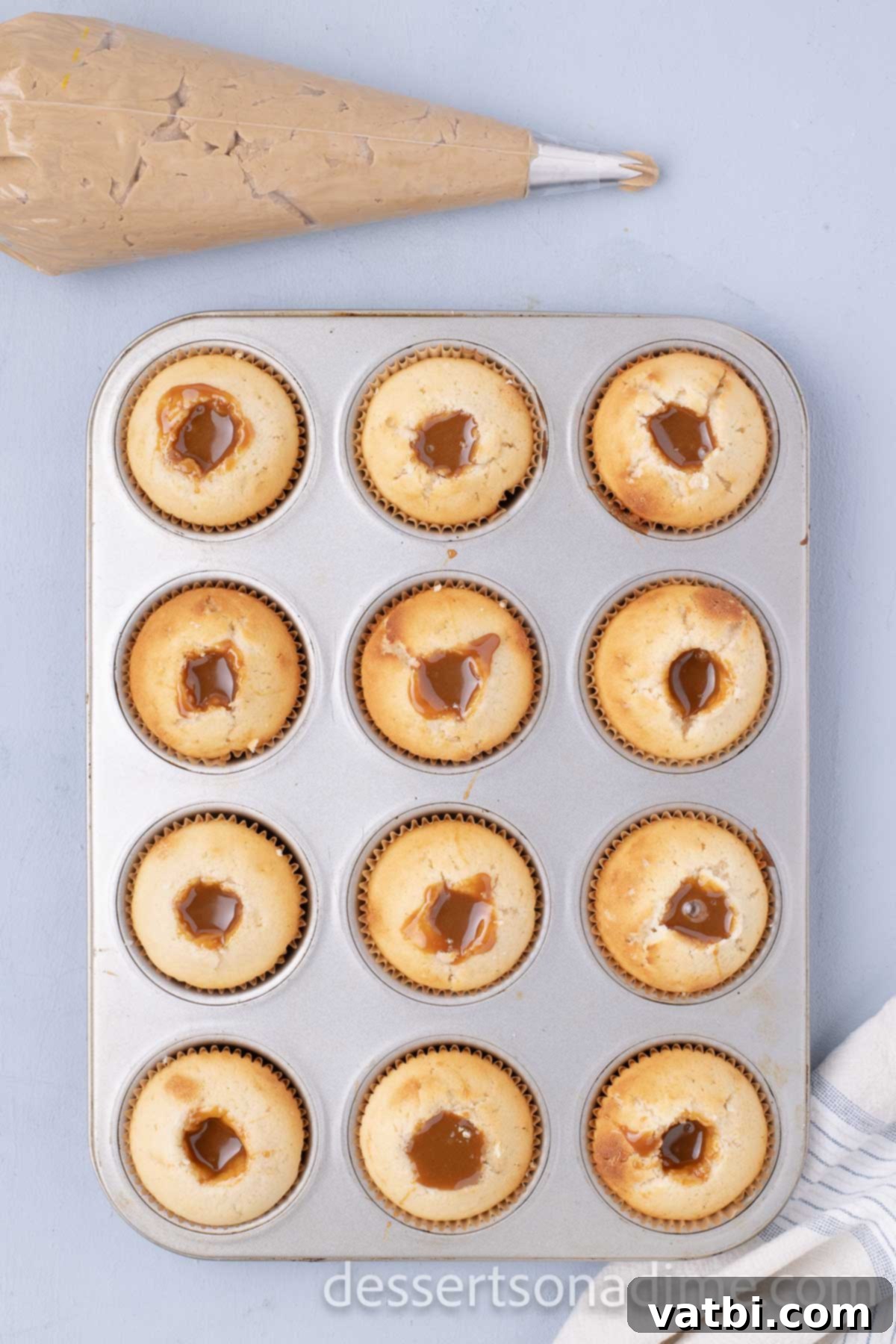 Decadent Salted Caramel Cupcakes 12 Salted caramel sauce being piped into the cored center of each cupcake.