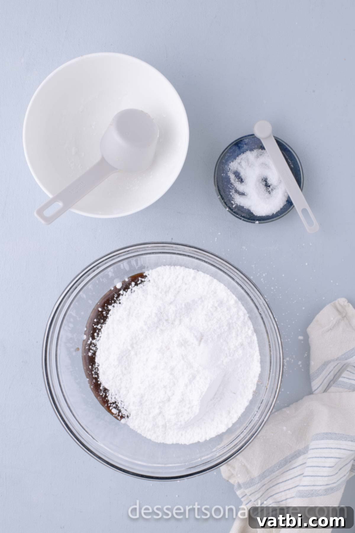 Decadent Salted Caramel Cupcakes 15 Powdered sugar being added to the cooled caramel mixture in a mixing bowl.