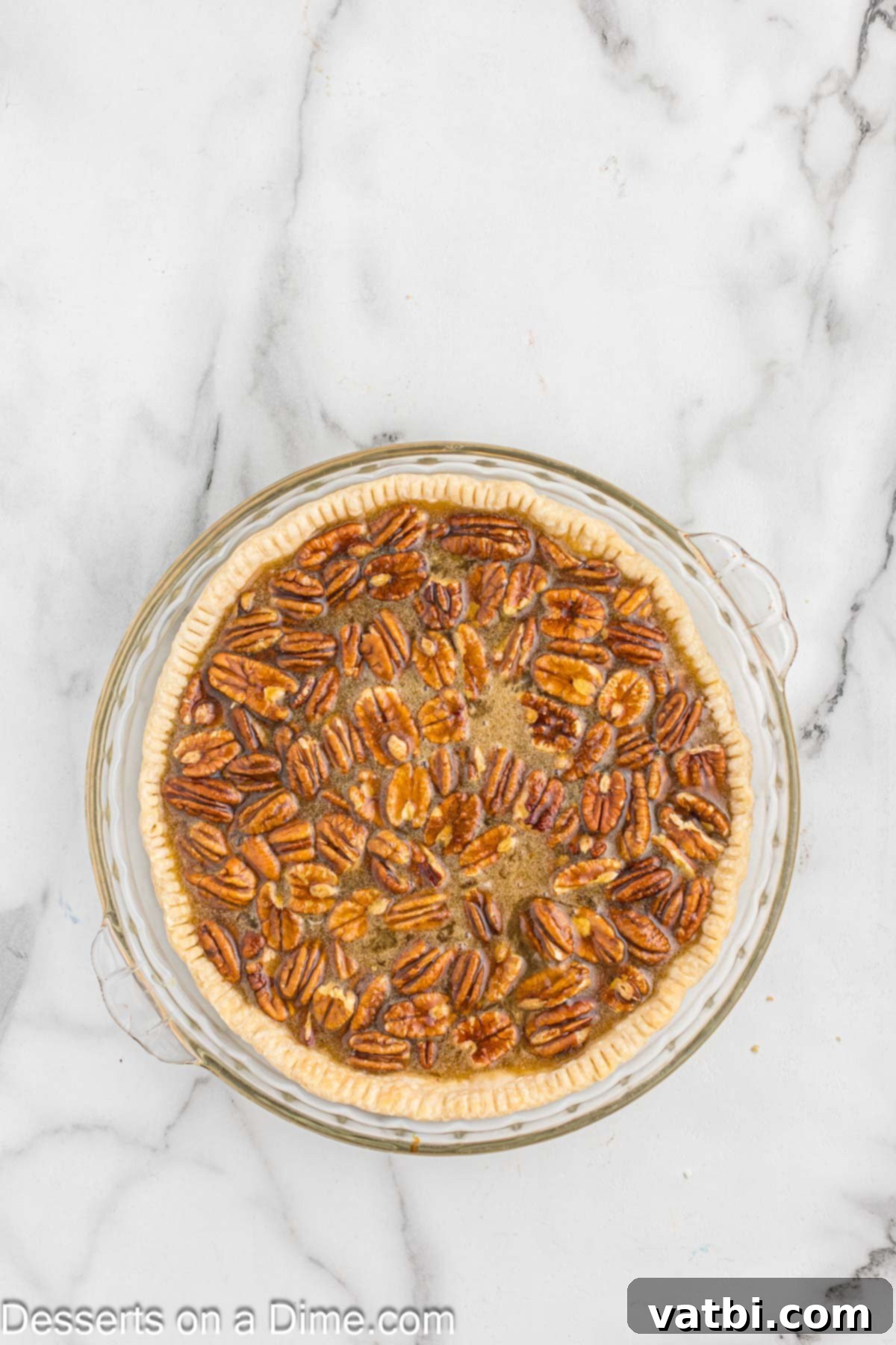 Paula Deen's Southern Pecan Delight 5 A smooth, amber-colored pie filling mixture is being poured over a bed of pecans in a pie plate, ready for baking.