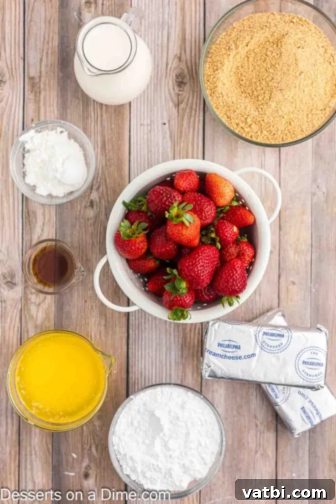 Easy No-Bake Strawberry Cheesecake 3 A flat lay photograph showcasing all the essential ingredients for making No Bake Strawberry Cheesecake, including graham cracker crumbs, a stick of butter, fresh, ripe strawberries, powdered sugar, cornstarch, a block of cream cheese, a bottle of vanilla extract, and a carton of heavy whipping cream.