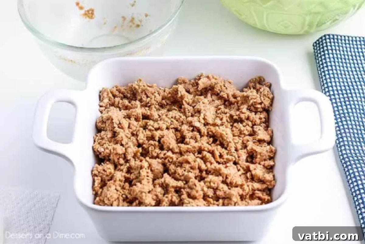 Irresistible Peach Crisp 5 Golden brown streusel topping sprinkled evenly over the peach filling in a baking dish, ready for the oven.