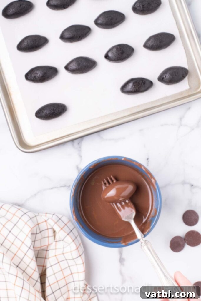Touchdown Oreo Truffles 6 An Oreo ball being dipped into melted chocolate using a fork, ensuring full coverage.