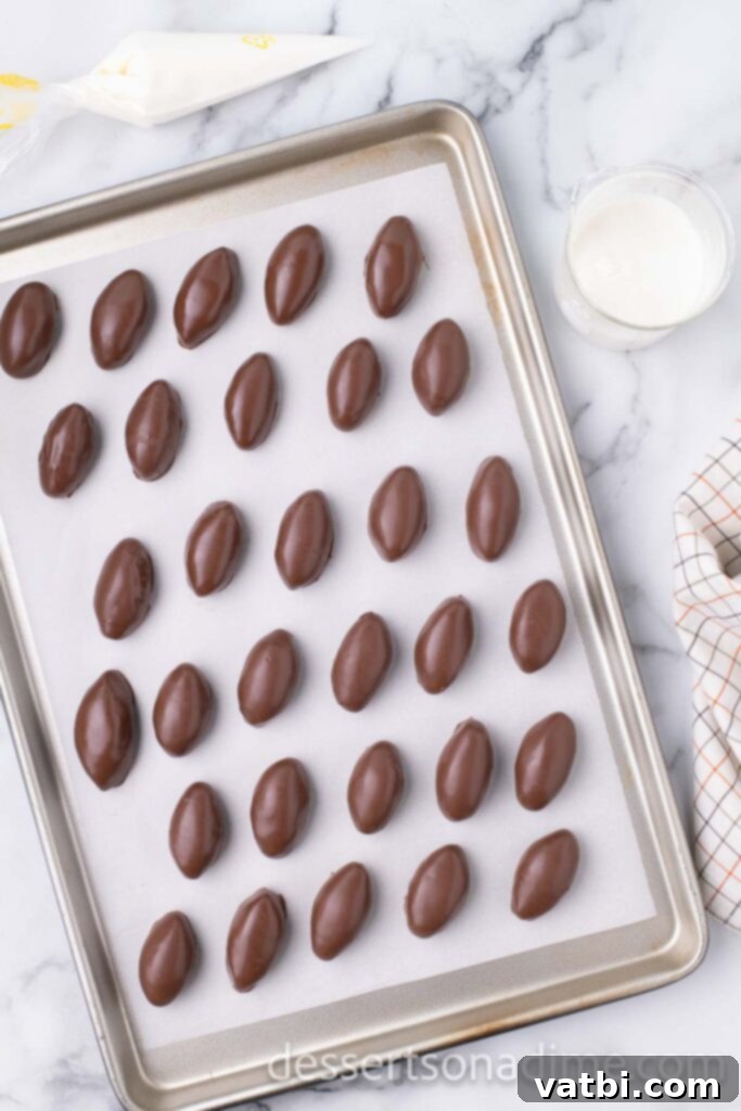 Touchdown Oreo Truffles 7 Chocolate-coated football-shaped Oreo balls on a wax paper lined baking sheet, setting.