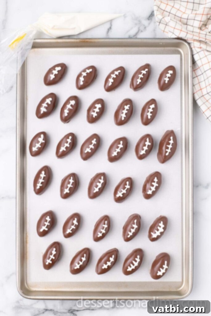 Touchdown Oreo Truffles 8 Football Oreo Balls on a wax paper lined baking sheet, chilling to set the chocolate coating.