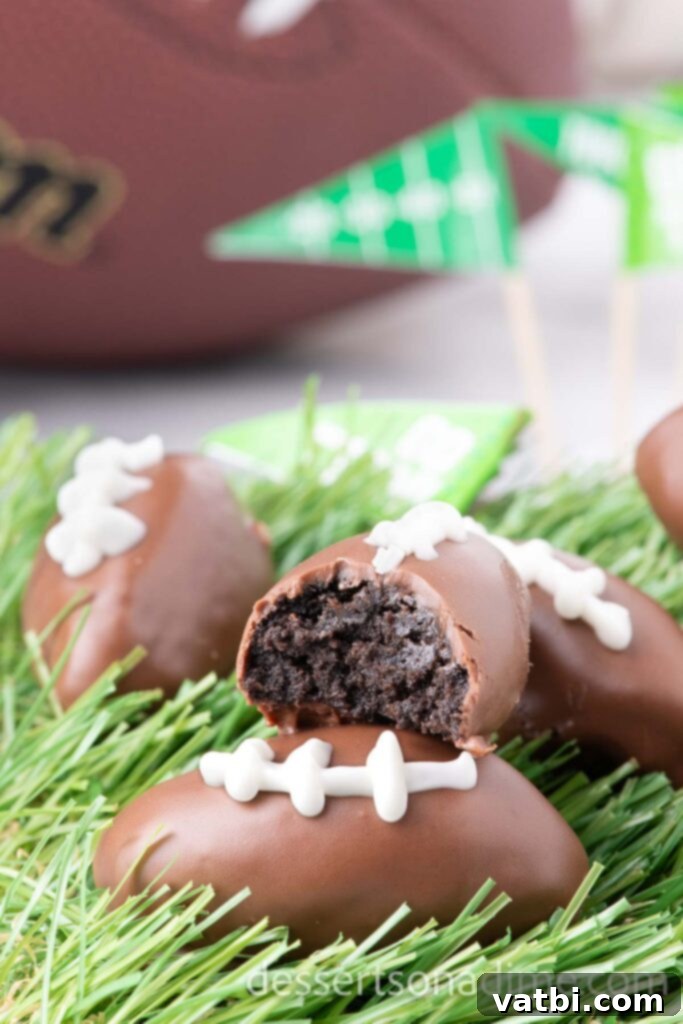 Touchdown Oreo Truffles 9 Festive Football Shaped Oreo Balls, some cut in half to show the creamy center, stacked on faux grass.