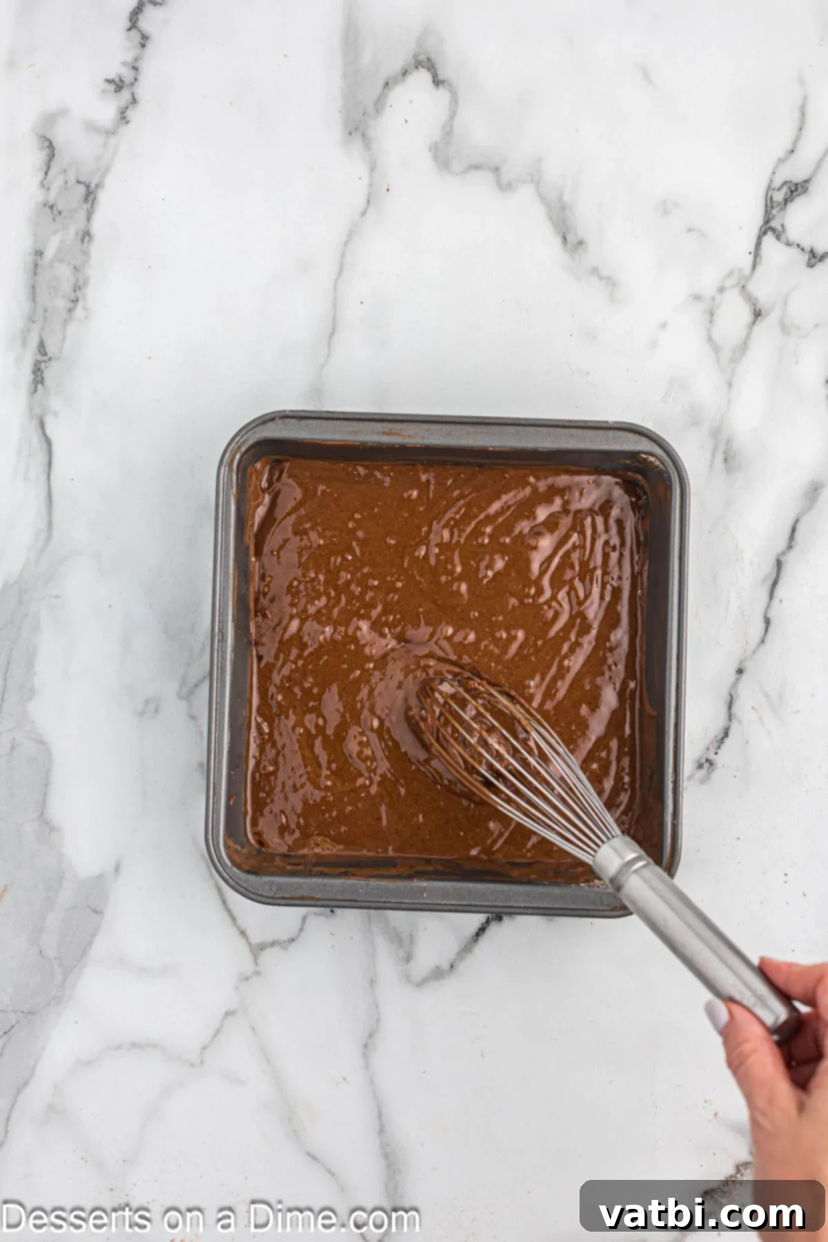 Crazy Simple Cake 7 Cake batter being whisked smoothly in a baking dish, ready for baking.