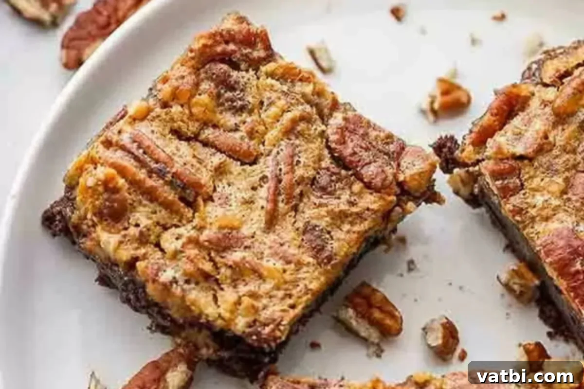 Pecan Pie Brownie Bliss 2 Pecan pie brownies cut and served on a white plate, showcasing the fudgy base and golden, nutty topping.
