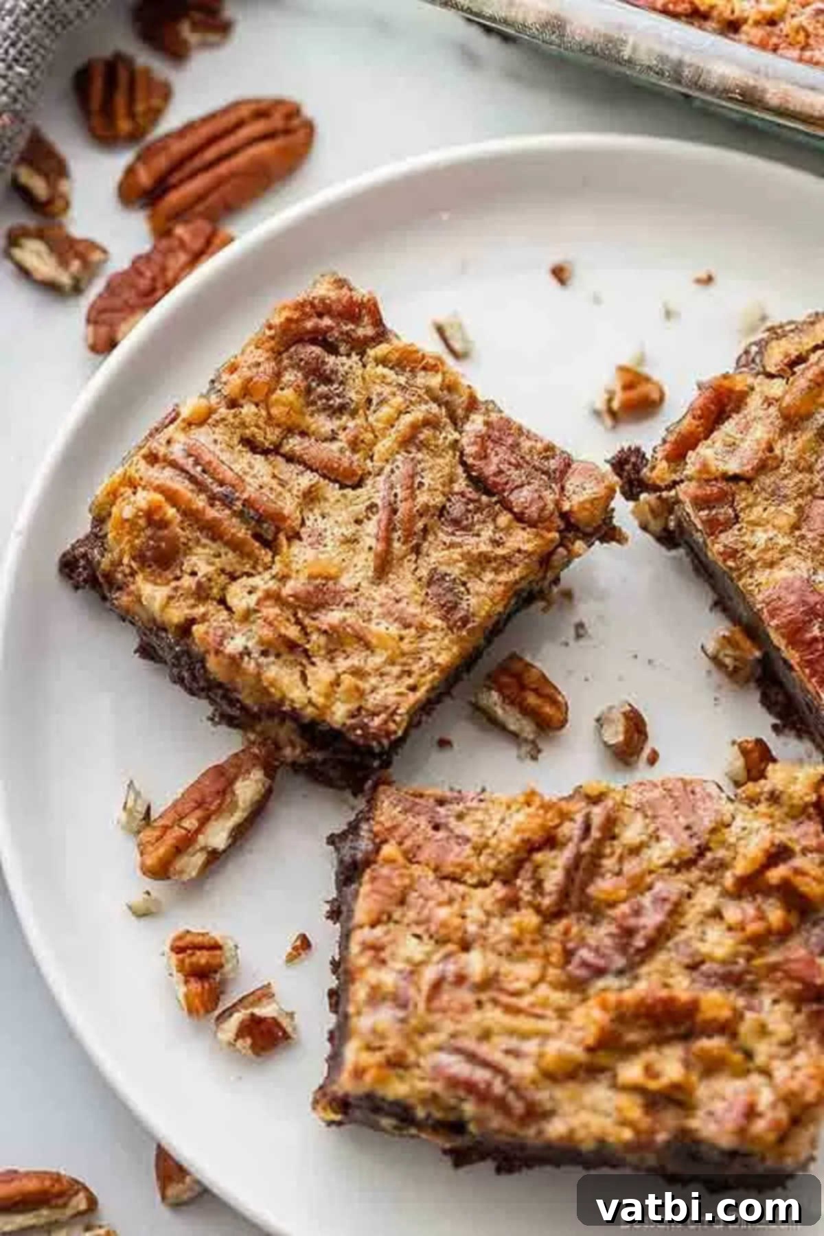 Everything you love about brownies and pecan pie comes together in this decadent Pecan pie brownies recipe. This dessert is irresistible. A close-up of Pecan Pie brownies on a white plate, highlighting the rich chocolate and gooey pecan layers.