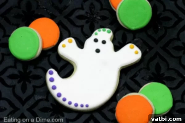 Halloween ghost cookies decorated with orange and green icing.