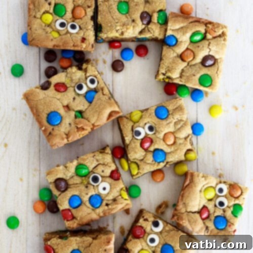 A bunch of cookie bars with colorful m & m's on top.