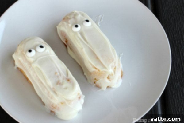 Two twinkies coated in white chocolate with eyes on them on a plate.