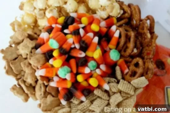 A bowl filled with candy corn, pretzels, and other snacks.
