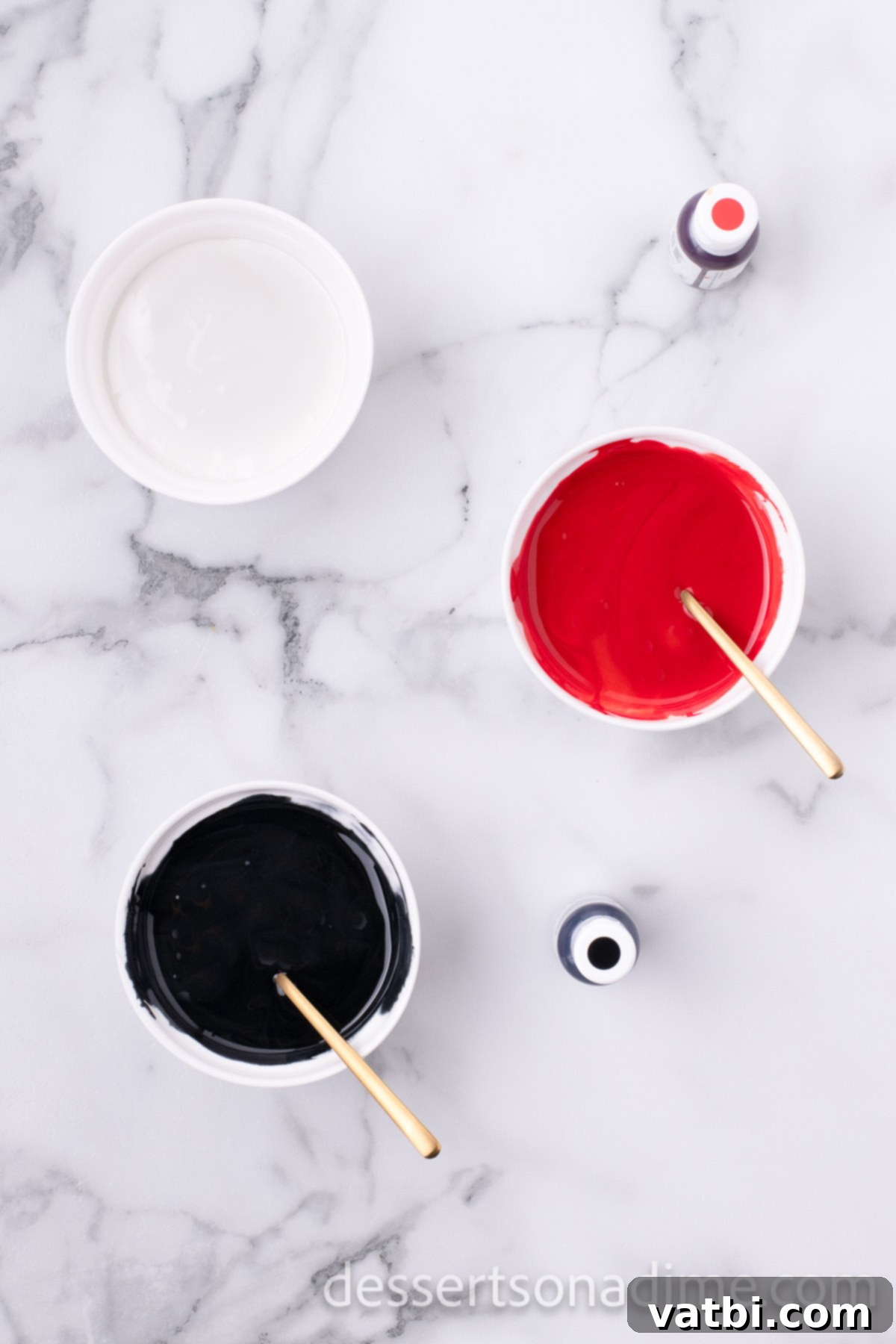 Magical Mickey Bakes 12 Royal icing divided into three bowls, colored red, black, and white for Mickey Mouse cookies.