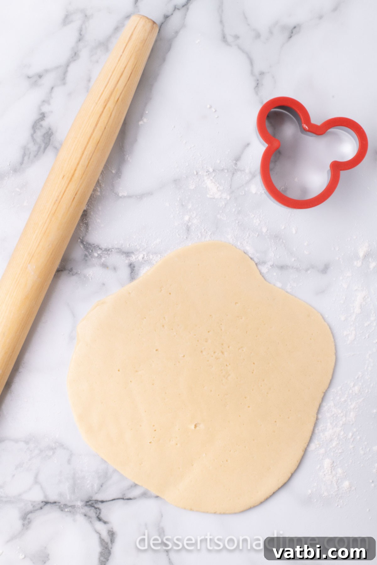 Magical Mickey Bakes 8 Cookie dough rolled out on a lightly floured surface with a rolling pin.