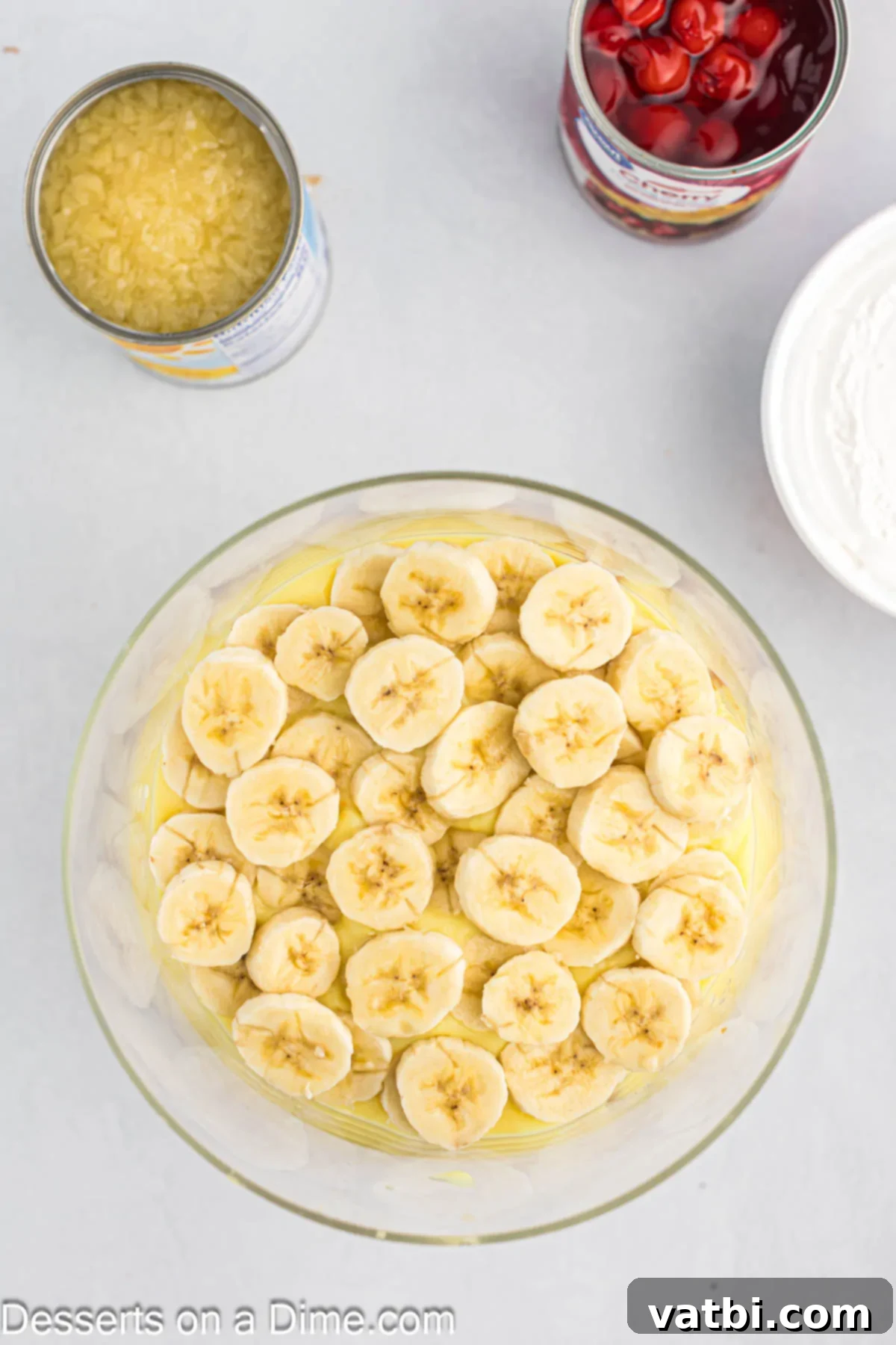 Party Punch Bowl Delight 6 A clear trifle dish with a layer of freshly sliced bananas evenly arranged over a layer of creamy pudding.