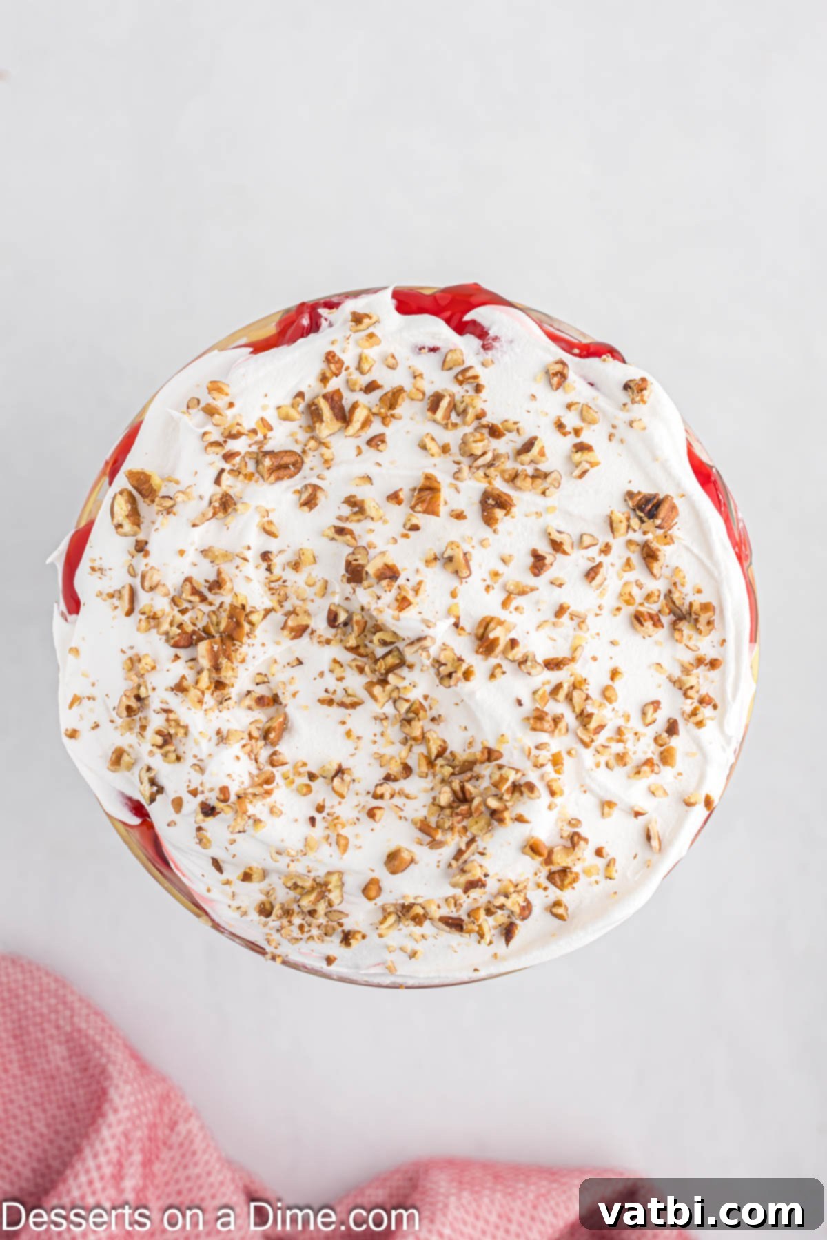 Party Punch Bowl Delight 8 The final layer of Punch Bowl Cake in a trifle dish, topped with generous swirls of whipped cream and a sprinkle of chopped nuts.