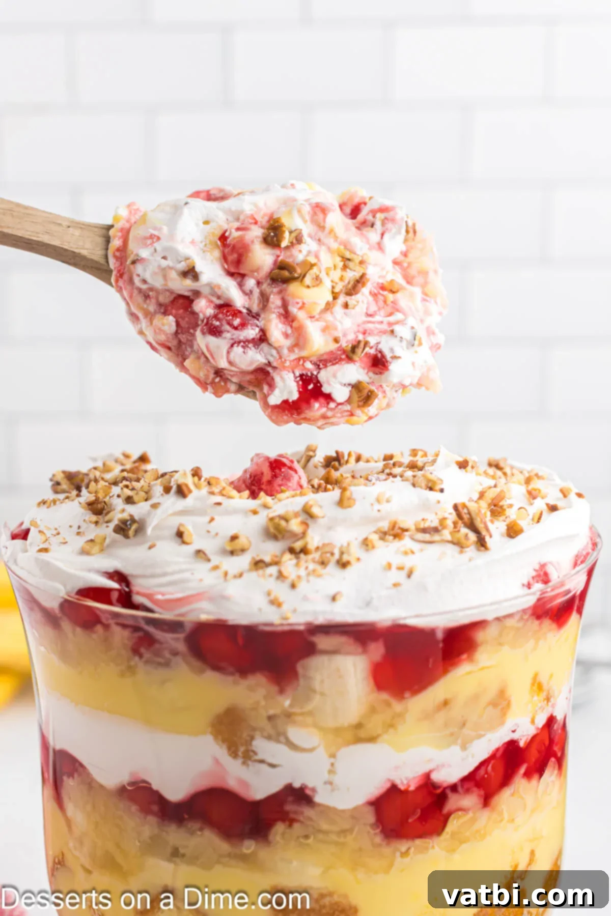 Party Punch Bowl Delight 10 A serving spoon lifting a spoonful of layered Punch Bowl Cake, showing all the components: cake, pudding, fruit, and whipped cream, ready to be enjoyed.