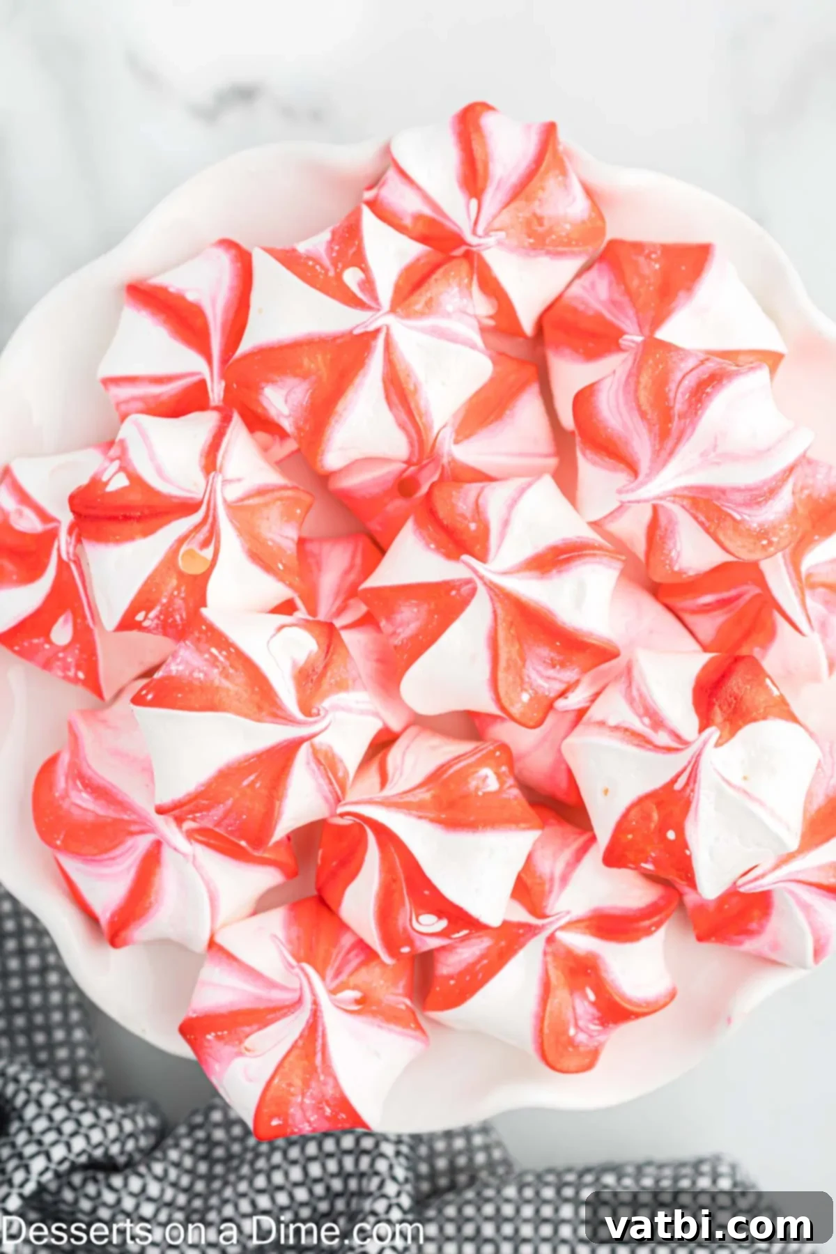 Crisp Peppermint Dream 8 A beautiful stack of red and white striped peppermint meringue cookies on a white platter, ready for serving.