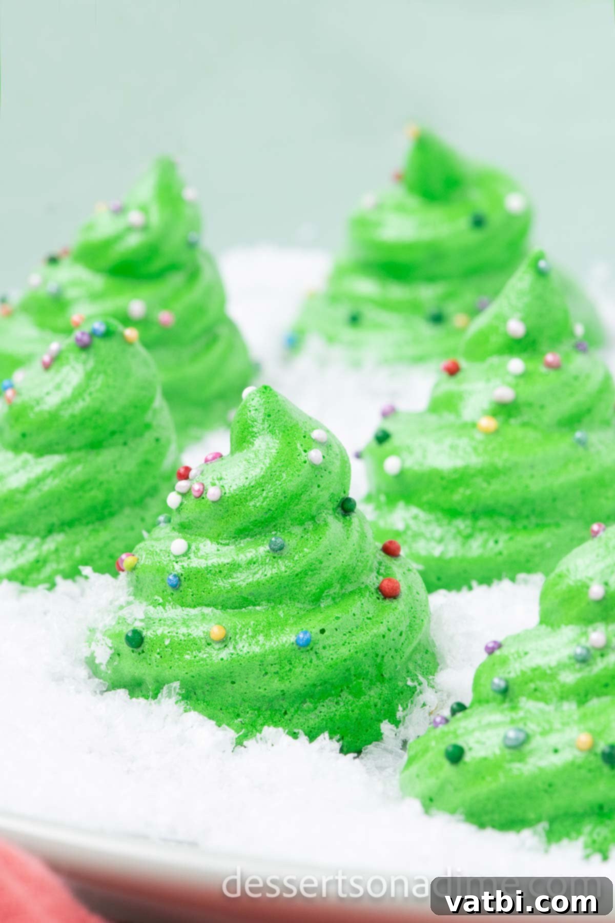 Sugar-Spun Christmas Trees 2 A festive platter of green Meringue Christmas Trees, dusted with powdered sugar, ready for holiday celebrations.