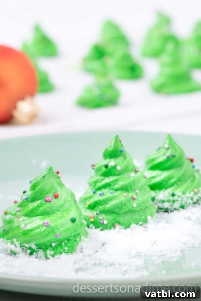 Sugar-Spun Christmas Trees 11 A row of perfectly piped and decorated Meringue Christmas Trees on a serving platter.