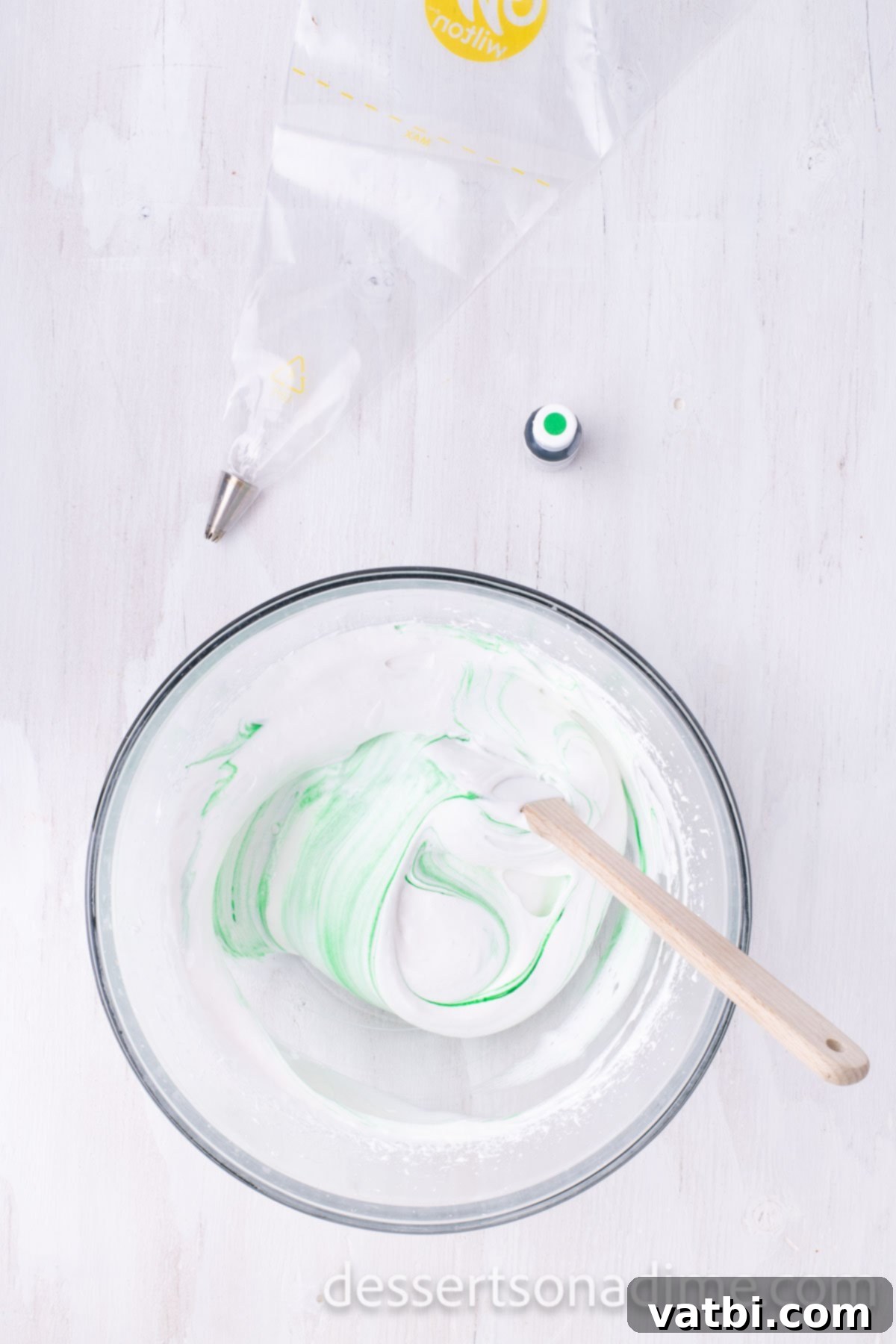 Sugar-Spun Christmas Trees 7 Green food coloring being gently folded into the white meringue in a bowl.