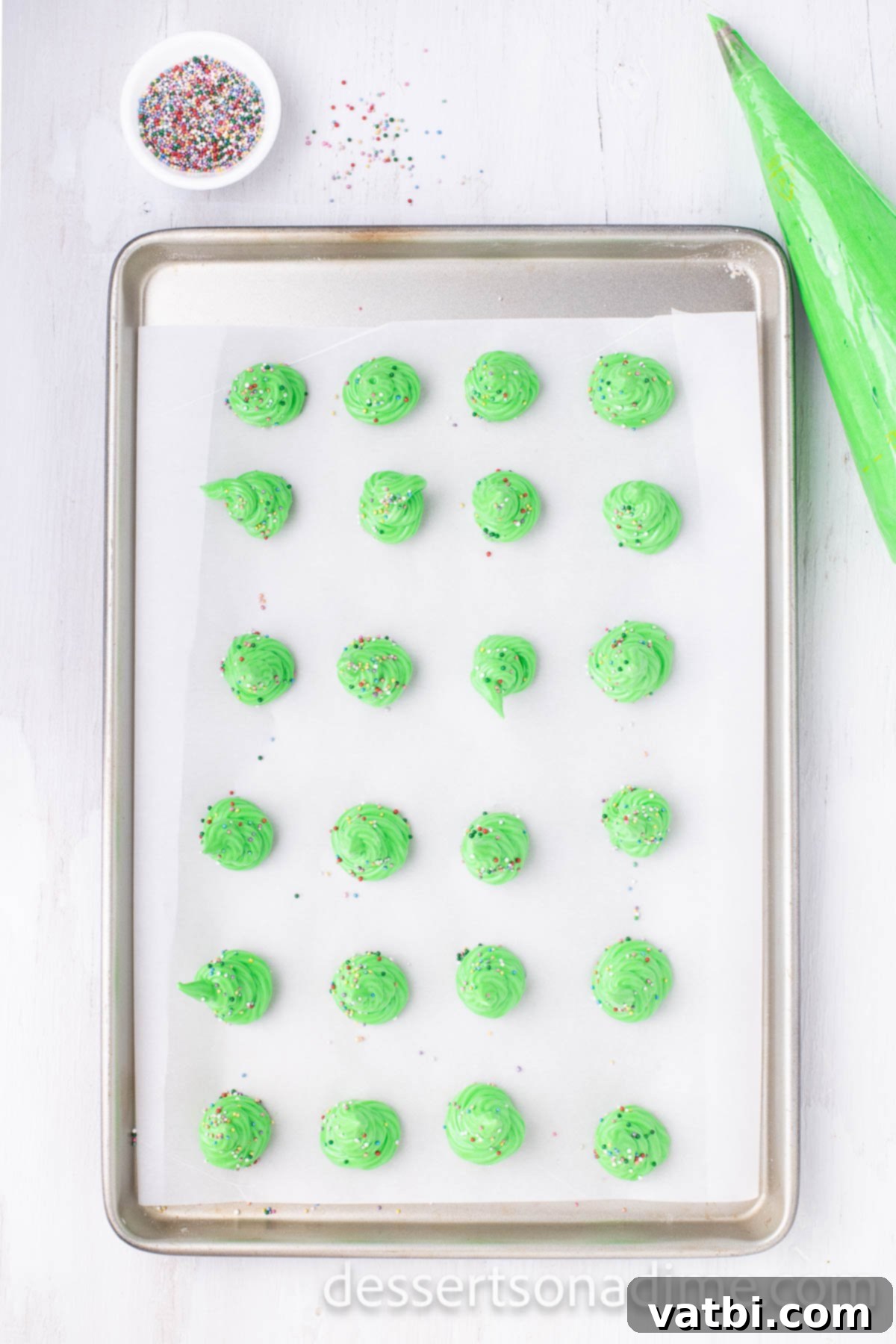 Sugar-Spun Christmas Trees 8 Christmas tree shaped meringues piped onto a parchment-lined cookie sheet, ready for baking.