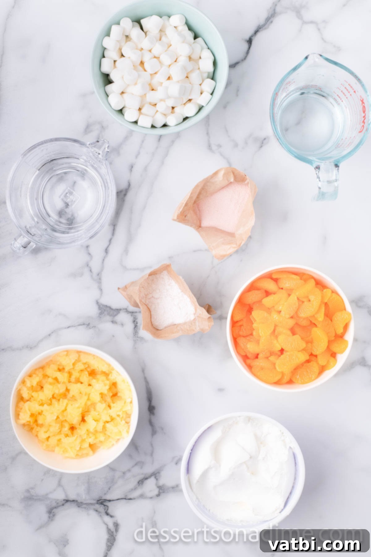 Tangerine Dream 3 A selection of ingredients laid out for orange fluff: mini marshmallows, canned mandarin oranges, crushed pineapple, whipped topping, and instant pudding mix, ready for preparation.