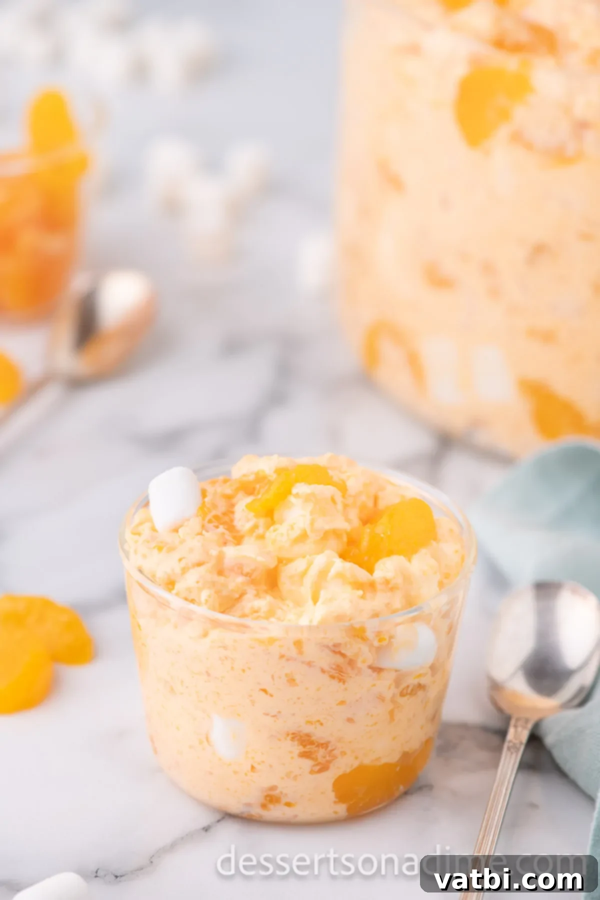 Tangerine Dream 9 An individual serving cup filled with vibrant orange fluff, garnished with a fresh mandarin orange segment, ready to be served.