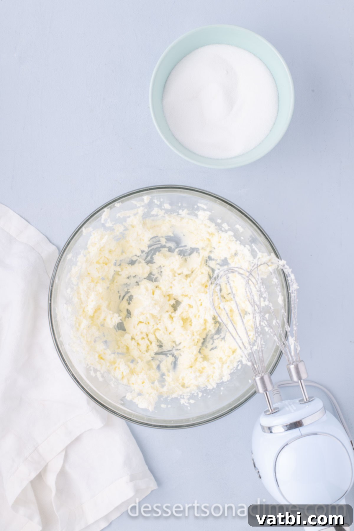 Eggs being added to the creamed butter and cream cheese mixture and blended.