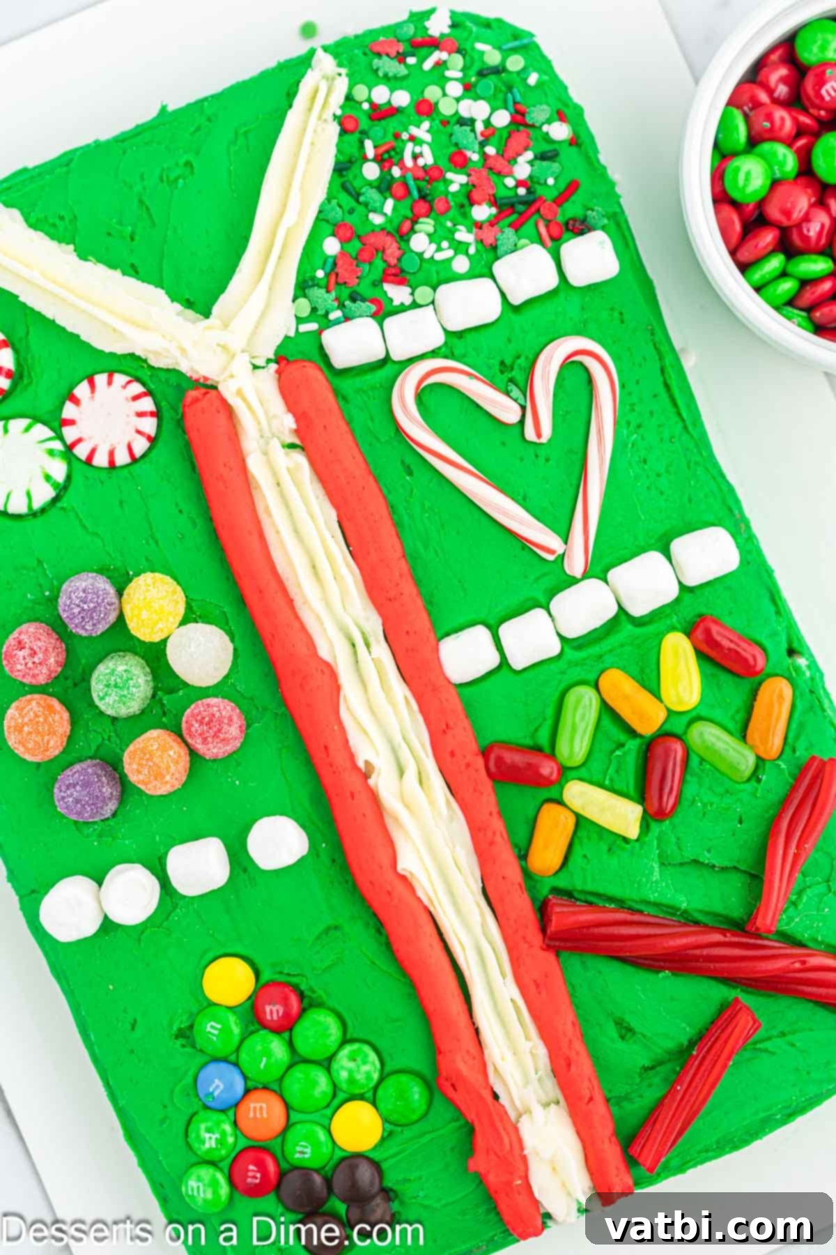 Ugly Sweater Cake on a platter, fully adorned with a vibrant array of various candy toppings and Christmas sprinkles, showcasing a completed festive design.
