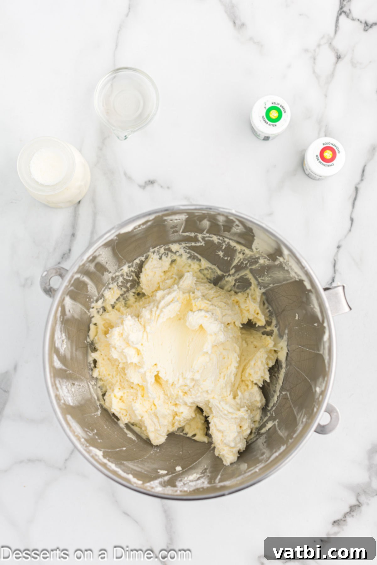 Powdered sugar being gradually mixed into creamed butter along with vanilla extract and heavy cream in a mixing bowl.