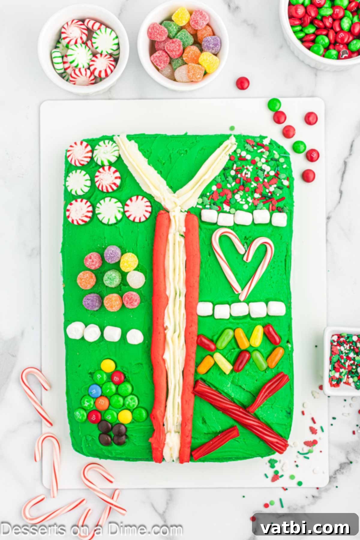 Ugly Sweater Cake on a platter with initial frosting and candy decorations, showcasing piped lines and early candy placement.