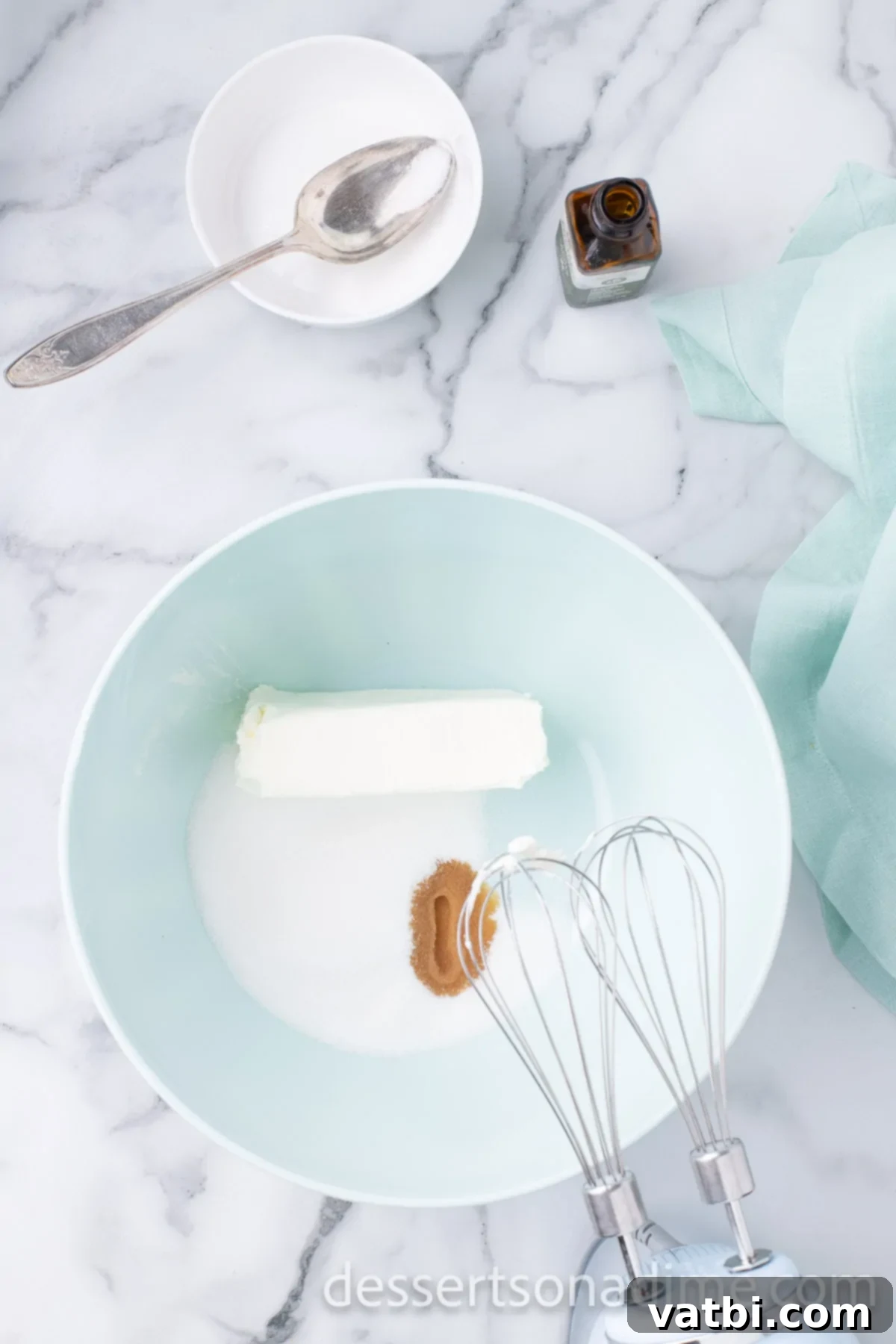 Crimson Craving 6 Bowl of cream cheese, sugar, and vanilla extract being combined with an electric mixer.