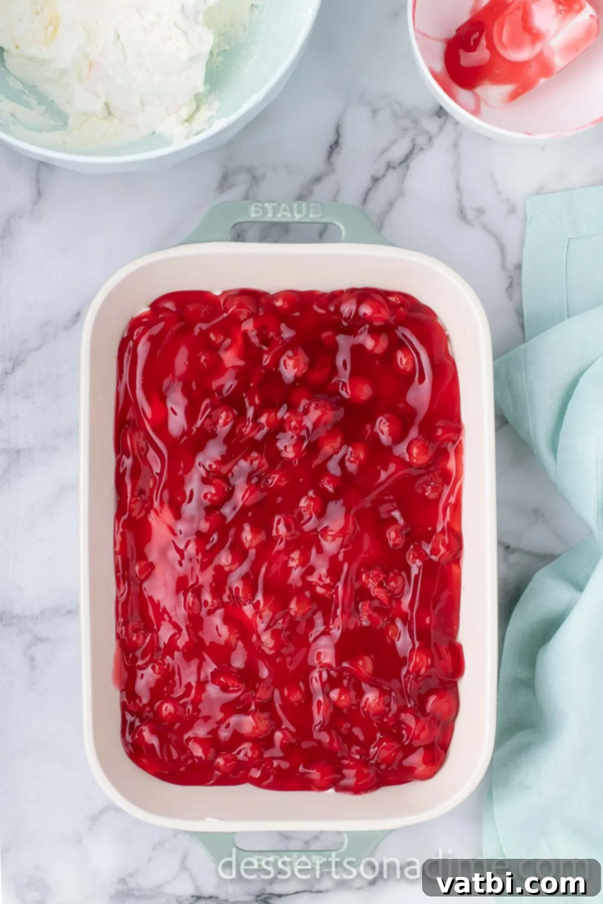 Crimson Craving 10 Cherry Pie Filling being spread on top of the first cream cheese layer.