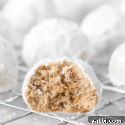 Piles of fluffy Snowball Cookies, also known as Mexican Wedding Cookies, dusted generously with powdered sugar on a white plate.