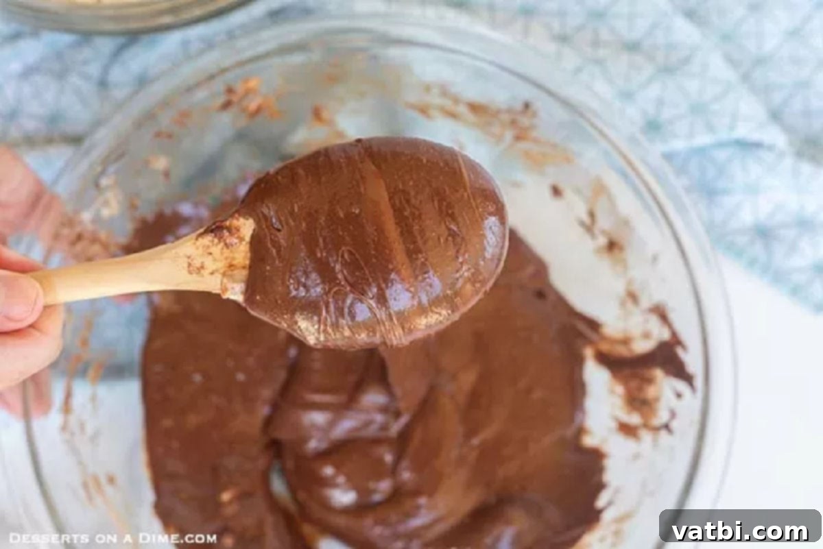 Decadent Chocolate Krispie Squares 2 Melted butter, marshmallows, chocolate chips, and cocoa powder combined in a microwave-safe bowl, forming a smooth, dark chocolate mixture.
