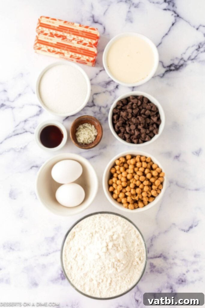 A vibrant display of ingredients for easy Twix Thumbprint Cookies: softened butter, chocolate chips, caramel bits, eggs, all-purpose flour, granulated sugar, and coarse sea salt.