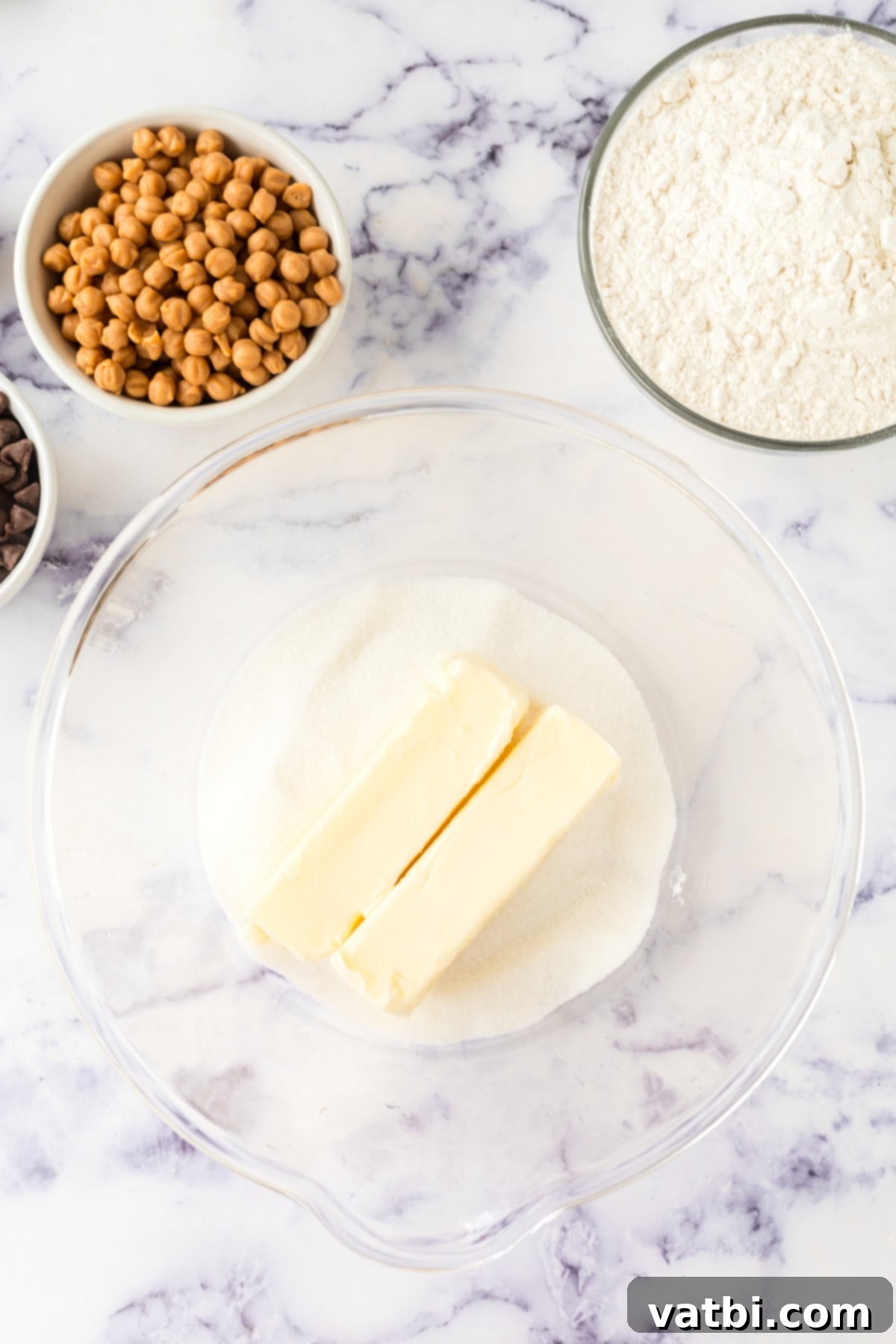 Softened butter in a mixing bowl with granulated sugar, ready to be creamed into a light and fluffy mixture.