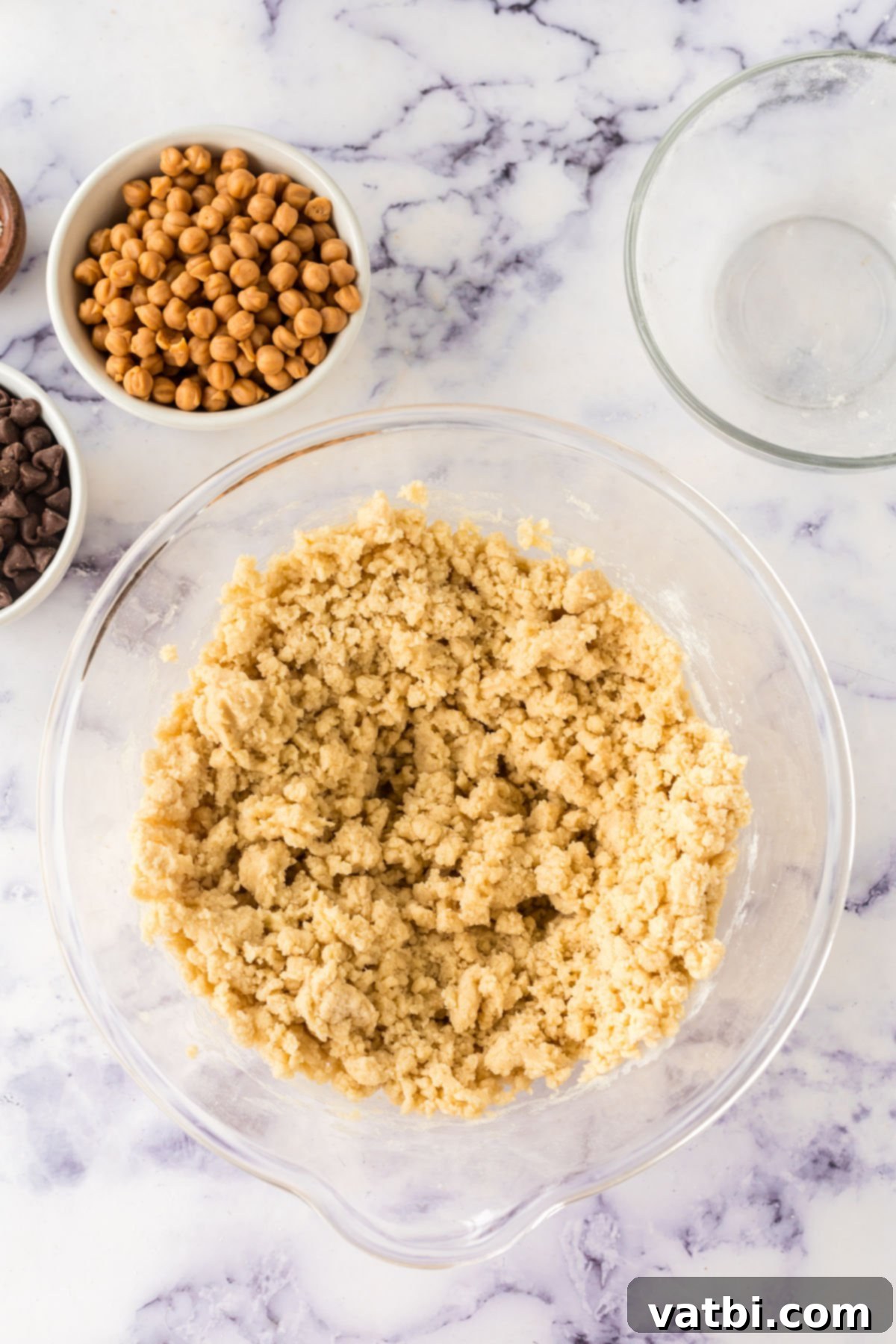 The combined wet and dry ingredients forming a soft cookie dough in a mixing bowl, covered with plastic wrap, ready for chilling.